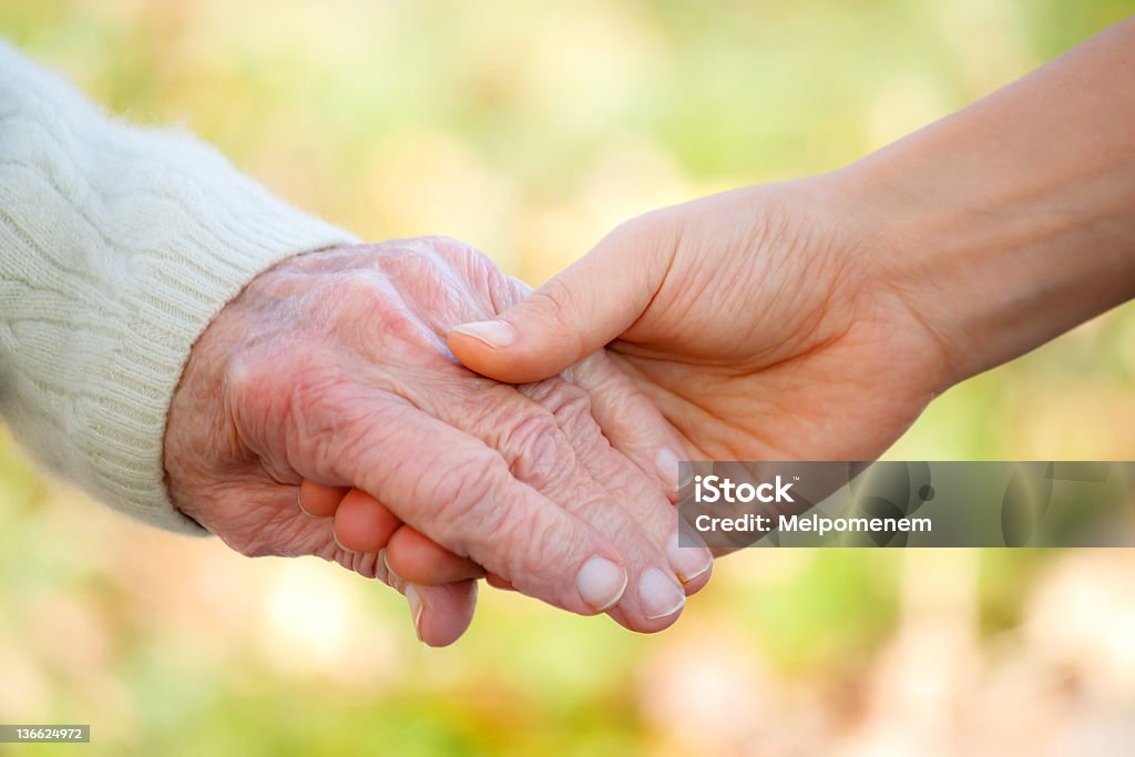Senior and young holding hands Senior and young holding hands outside A Helping Hand Stock Photo