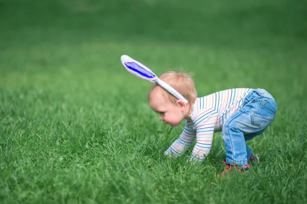 Toddler egg hunter close-up in grass with bunny ears... Toddler egg hunter close-up in grass with bunny ears. baby gun stock pictures, royalty-free photos & images
