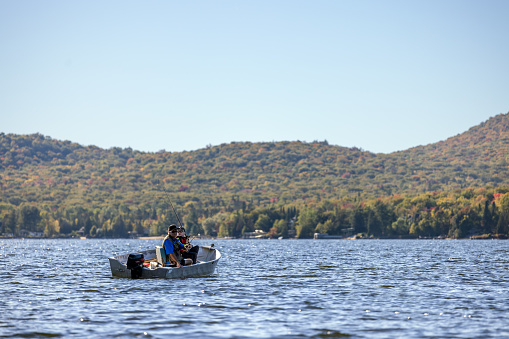 Abuelo y nieto pescando en su bote de pesca en el lago en otoño, Quebec, Canadá photo
