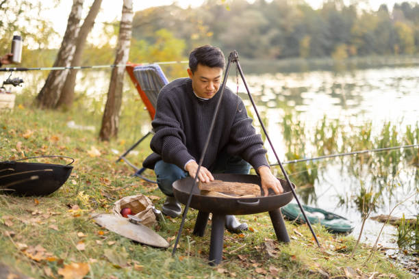 istock Man making fire in grill for cooking at nature 1366254351