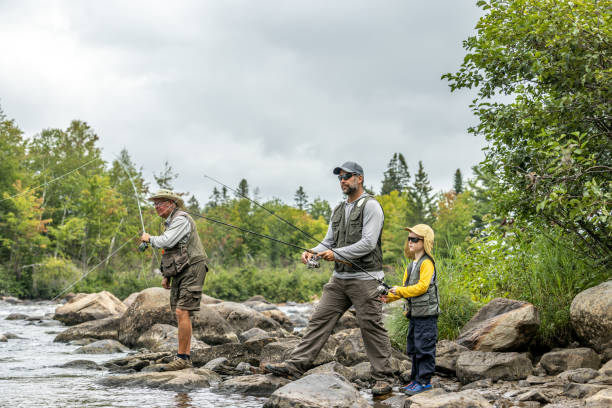 mignon garçon enfant, son père et son grand-père pêchant dans la rivière au québec - fishing lake grandfather grandson photos et images de collection