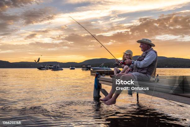 Grandfather And Grandson Fishing At Sunset In Summer Quebec Canada Stock Photo - Download Image Now