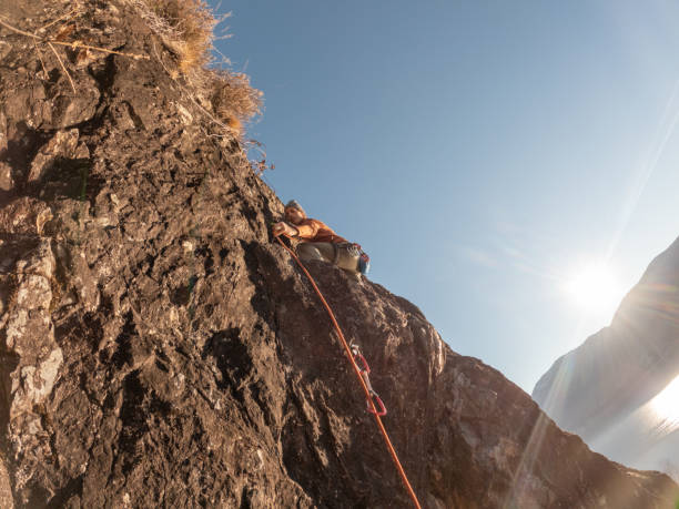 istock Mountain climber ascend rock face at sunrise, moving up 1366256315