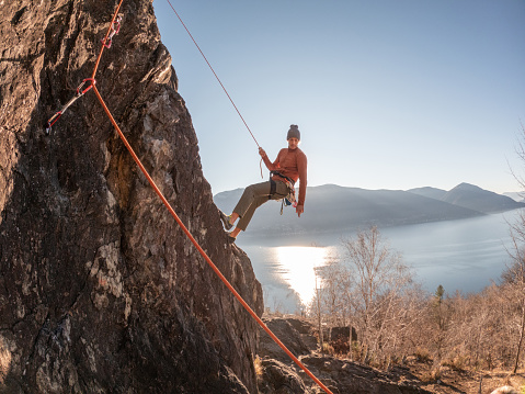 Mountain climber rappels on rock face