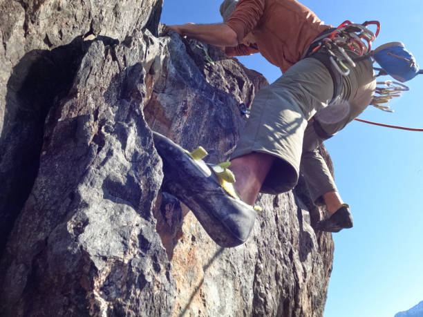 istock Mountain climber ascend rock face at sunrise, moving up 1366256513