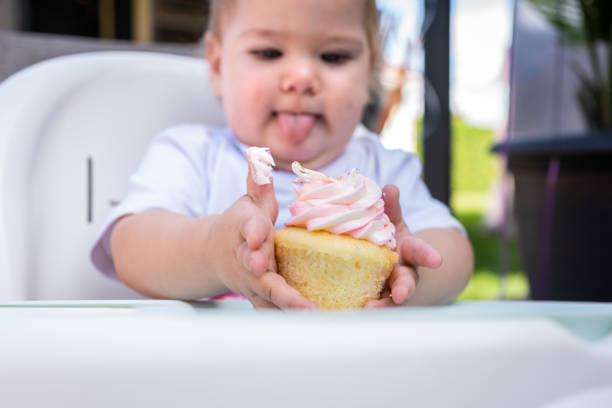 Baby girl eating a cake for her first anniversary celebration.
