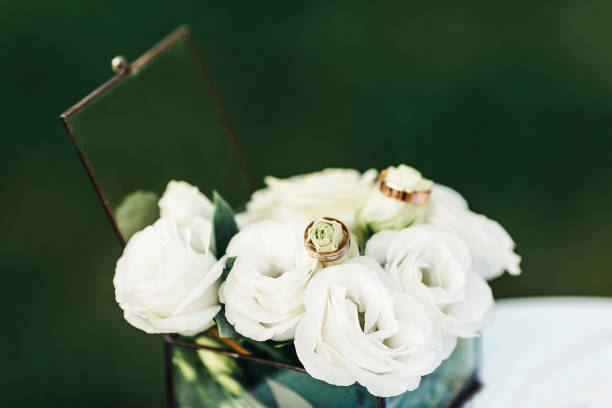 istock wedding rings lie on white eustomas in a glass casket. wedding ceremony concept 1366259652