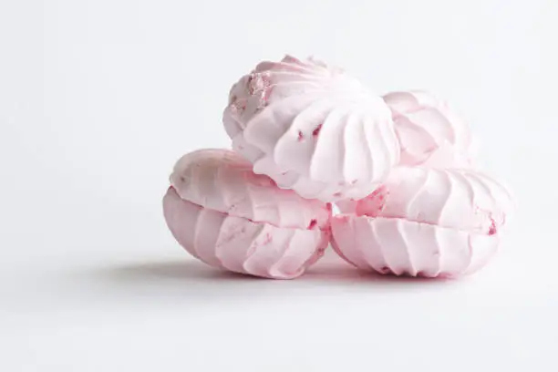 Delicate pink fruit and berry marshmallow lies on a white background. Free space for an inscription. Natural lighting in the kitchen. Close-up