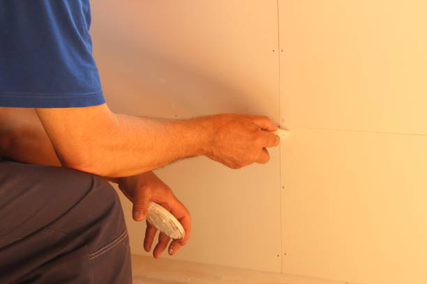 The man covers the cracks with putty. Finishing works at home. stock photo