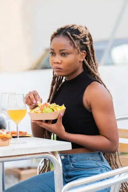 Photo of Woman enjoying nachos and guacamole with drinks