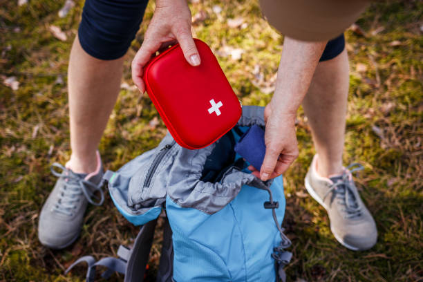 Woman taking out first aid kit from backpack stock photo