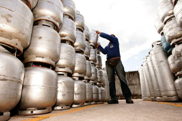 eunapolis, bahia, brazil - march 16, 2010: worker at a kitchen gas dealer sorts cylinders in the company's patio.