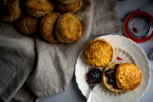 Freshly baked homemade scones served with cherry-cranberry preserves on an antique plate.