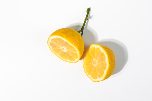 Yellow lemon citrus fruit cut in half on white background