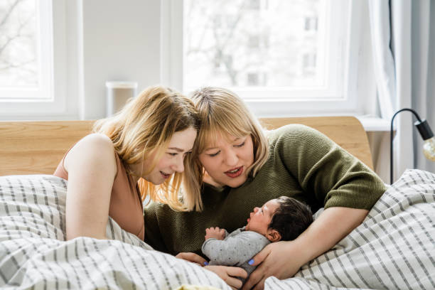 Lesbian couple with their baby boy lying in bed stock photo