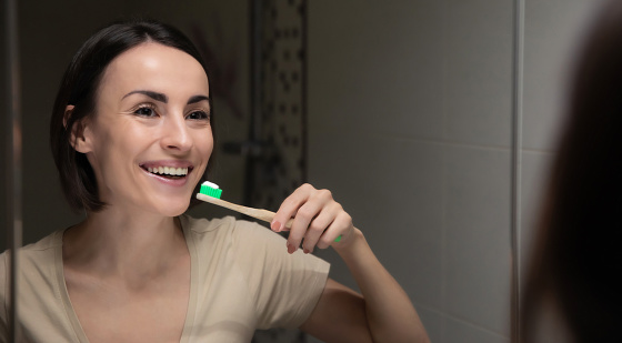 Close up portrait of a beautiful healthy woman while she cleaning her teeth with help of a toothbrush in the bathroom