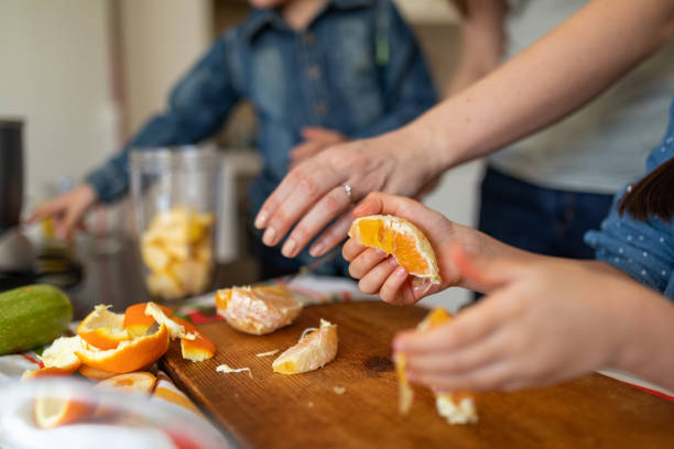Unrecognizable family making an orange juice in domestic kitchen