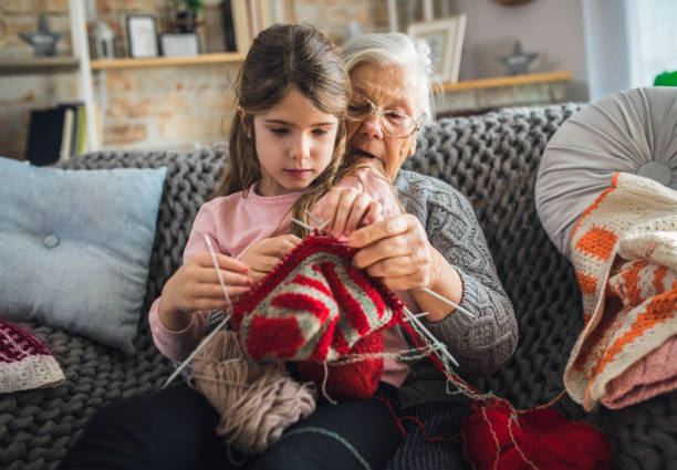 Granny teach granddaughter knitting with needles stock photo