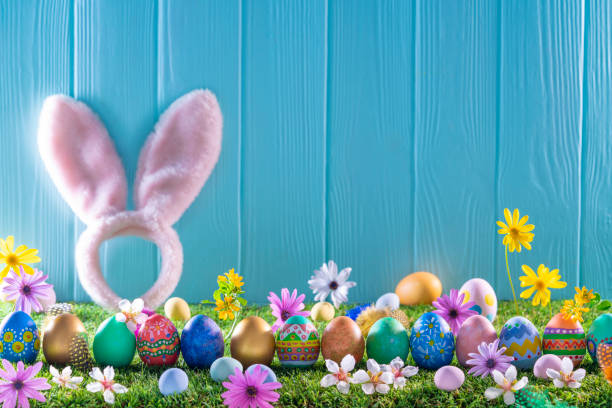 istock Easter eggs on turf grass and blue wooden wall with spring flowers 1366287719