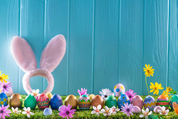 istock Easter eggs on turf grass and blue wooden wall with spring flowers 1366287813
