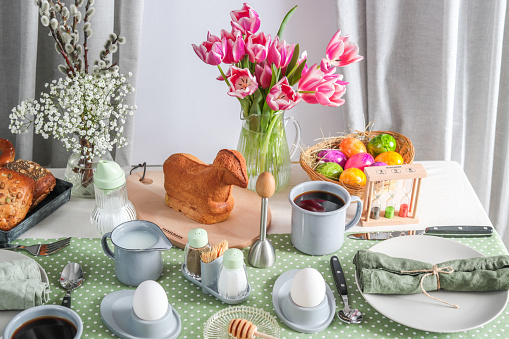 Easter Sunday brunch breakfast table setting with coffee, Easter lamb cake and tulips