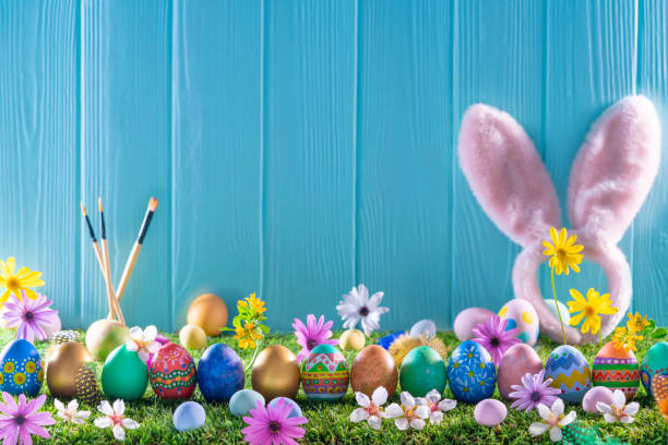 istock Easter eggs on turf grass and blue wooden wall with spring flowers 1366287925