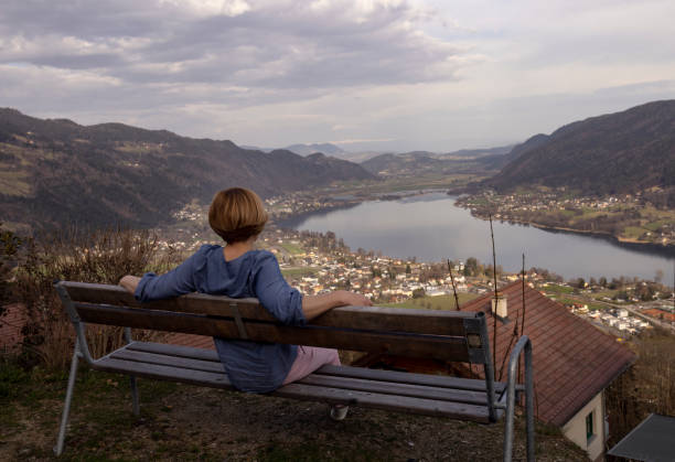 女性は湖のほとりのベンチに座っている - bench mountain park sitting ストックフォトと画像