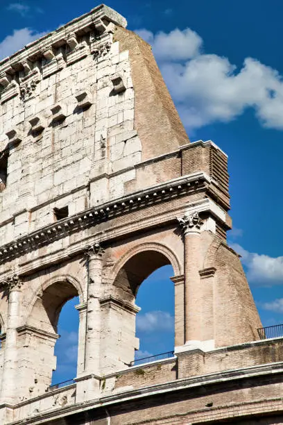 Rome, Italy. Arches archictecture of Colosseum (Colosseo) exterior with blue sky background and clouds.