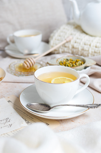 Fresh chamomile honey and ginger tea cups with lemon in cozy rustic kitchen