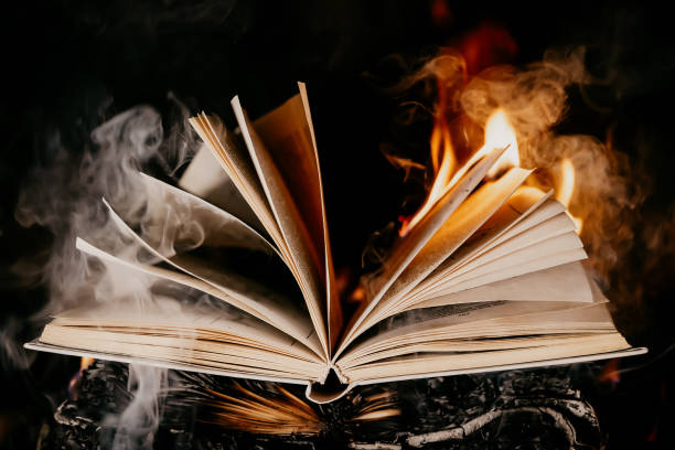 istock Old open book is burning. Big bright flame on papers. Destruction of diary in fireplace. Renunciation of past. Forbidden literature on bonfire. Censorship, prohibition of freedom information 1366290405