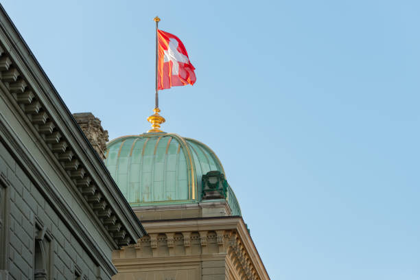 the swiss flag on the federal parliament building in Bern the flag waving in the wind above one of the domes of the Bundeshaus building. 02/21/2021 - Bundesplatz, 3011 Bern, Canton Bern, Switzerland bundeshaus stock pictures, royalty-free photos & images