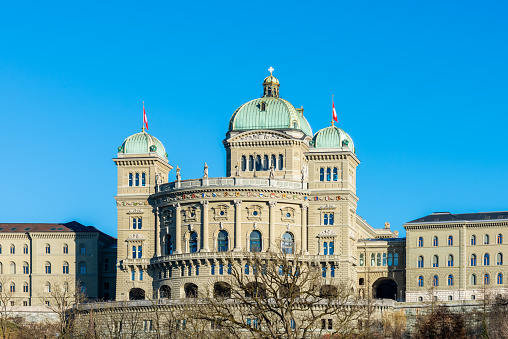 View of the southern facade of the Federal Parliament building under a blue sky, view of the government building from the Aare river. 02/21/2021 - Dalmaziquai, 3005 Bern, Canton Bern, Switzerland