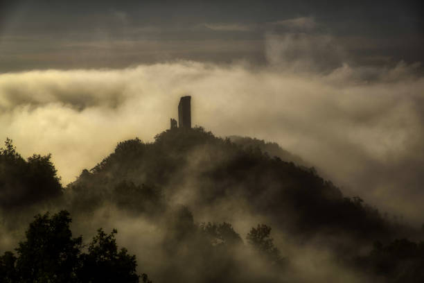 os restos de um castelo medieval envolto em neblina como em um filme de terror halloween - mist castle fog night - fotografias e filmes do acervo