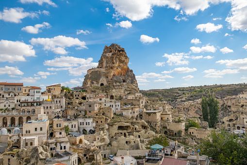 Ortahisar castle or central castle and fairy chimneys in Cappadocia, Turkey at sunset. Ortahisar Castle and traditional houses carved stone. Cave houses in fairy chimneys.