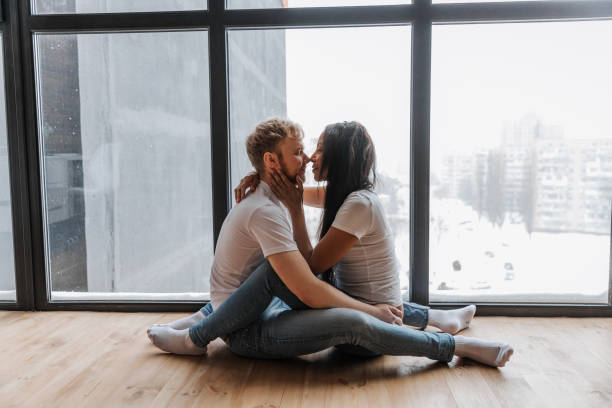 zakochana para czule przytula się w przytulnym otoczeniu domowym i panoramicznym oknie - passion kissing black white zdjęcia i obrazy z banku zdjęć