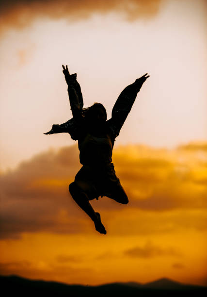 istock Woman, is dancing and spinning, while silhouetted against the evening sky 1366298198