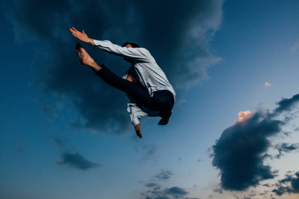 istock Athletic dancer in a shirt while jumping above the sky 1366298238