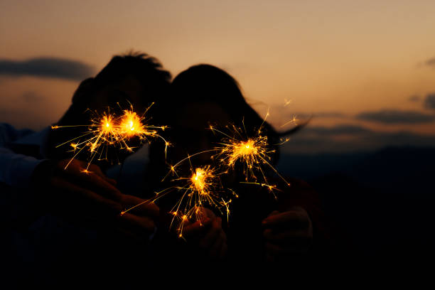 istock Young silhouette couple having fun with some firecracker at mountain 1366298250