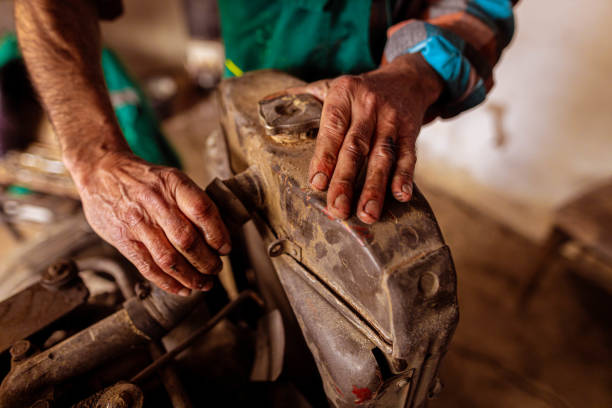 At garage unrecognizbale senior male farmer, preparing and adjusting his tractor for a working spring season