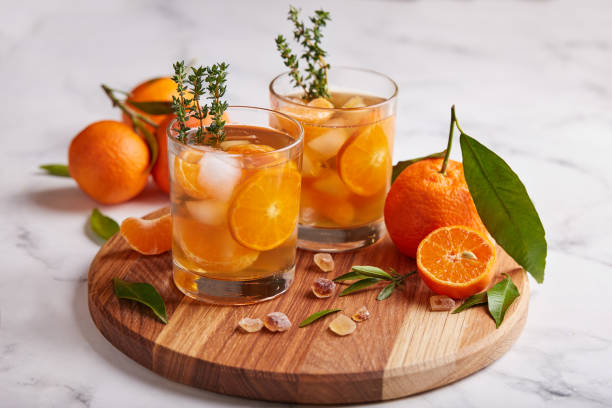 ice tea with orange juice, ice cubes, and thymes. refreshed summer beverage. - chá gelado imagens e fotografias de stock