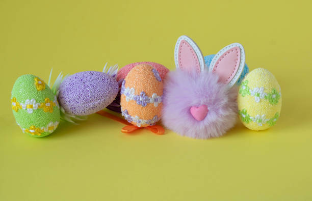 istock Colorful Easter eggs and a cute fluffy lilac toy rabbit on a yellow background. Easter Concept 1366309353