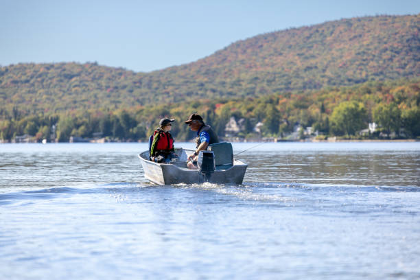 grand-père et petit-fils pêcheurs dans leur bateau nautique sur le lac en été, québec - fishing lake grandfather grandson photos et images de collection