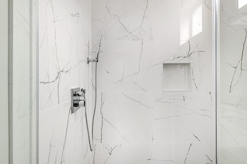 Ducha de azulejos de mármol blanco y gris con cerramiento de puerta de vidrio photo