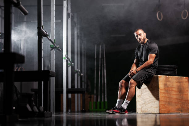 istock Muscular athlete posing with weightlifting equipment. Smoke background 1366315770