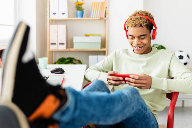 Addicted young teenage man playing video games on mobile phone app at home stock photo