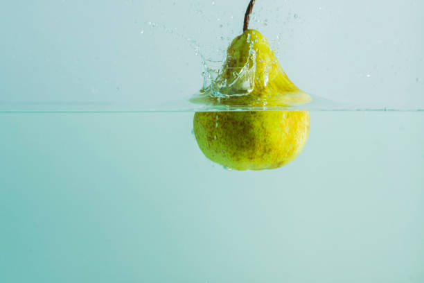 bottle with water and a glass with two pears in an allegory of a refreshing pear juice