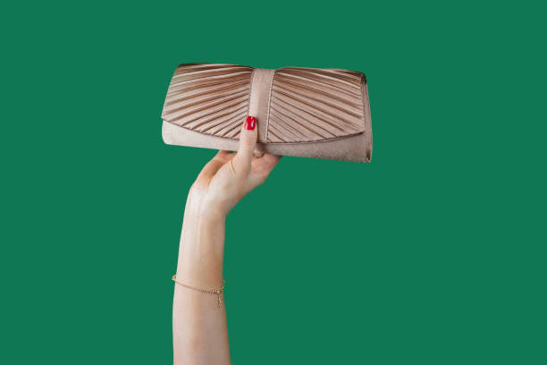 the girl holds in her hand a stylish modern golden clutch in her hand on a green background the girl holds in her hand a stylish modern golden clutch in her hand on a green background clutch bag stock pictures, royalty-free photos & images