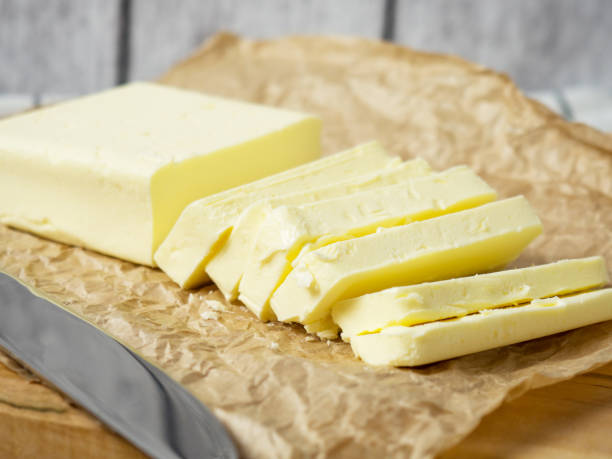 istock Fresh butter block sliced on wooden cutting board on rustic background 1366324268