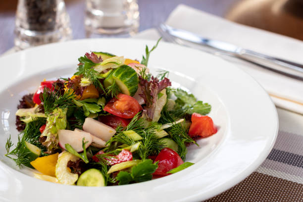 istock Green vegetable salad with tomatoes on white plate 1366325109