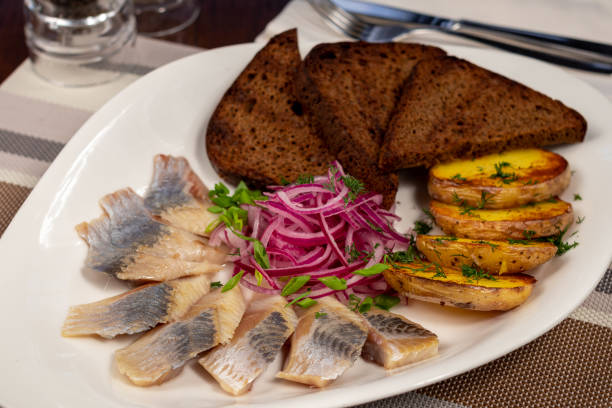 istock Herring with potatoes, red onion and black bread on white plate 1366325128